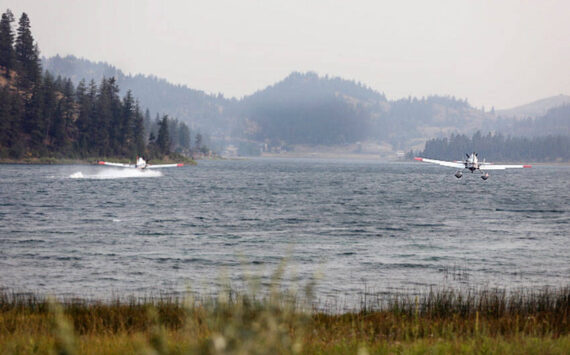 Two water-bomber planes gather water from Wannacut Lake to fight flames at the Rainbow Lake Fire on Palmer Mountain and the Wannacut Fire. The Rainbow Lake Fire was listed at 150 acres on Tuesday afternoon and the Wannacut lake fire was listed at 64 acres. Smoke from these fires and larger fires in the Methow, Chelan and lower British Columbia areas has settled in the Okanogan Valley. <em>Laura Knowlton/staff photo </em>